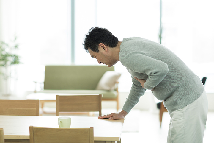 胸が苦しくテーブルに手をつく男性